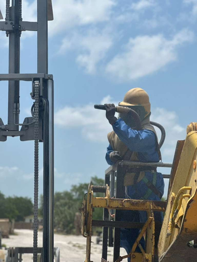 Technician blasting a forklift mast from a man lift