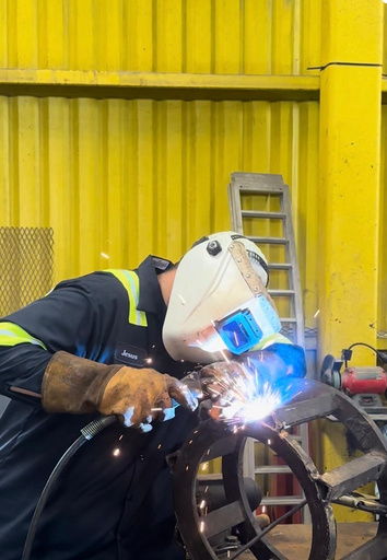 QuipCo welder MIG welding a steel ring assembly in the shop