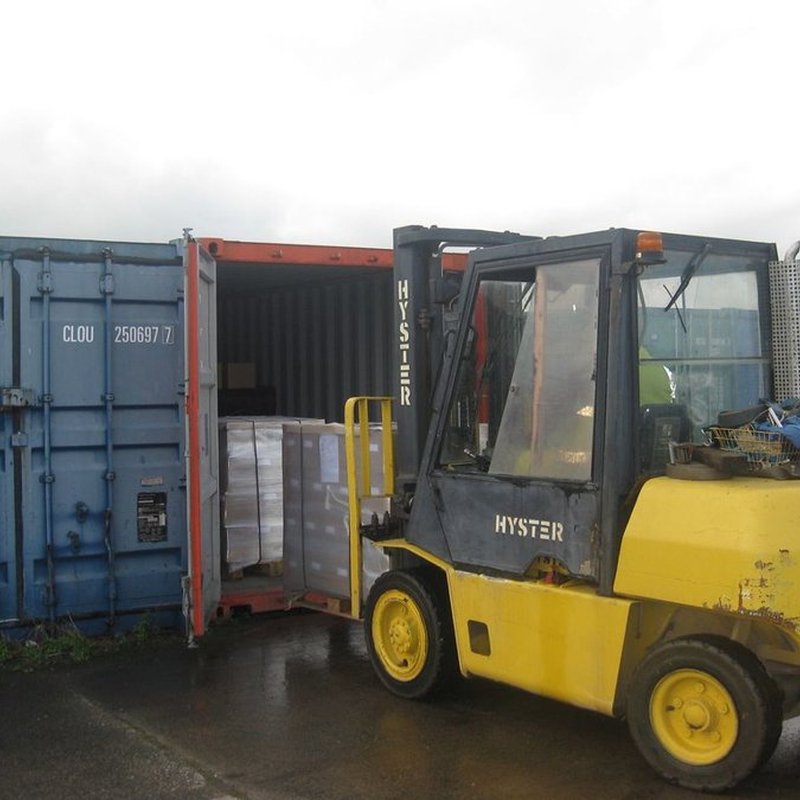 Yellow forklift loading a shipping container