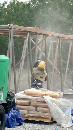 Crew member blasting a large steel truss frame